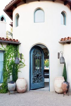 an entrance to a house with potted plants on the outside and large doors in front