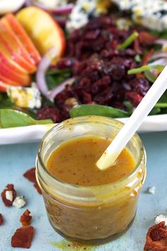 a glass jar filled with dressing next to a salad