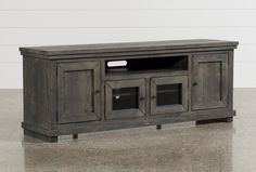 an old wooden entertainment center with glass doors on the front and side panels, sitting on top of a concrete floor