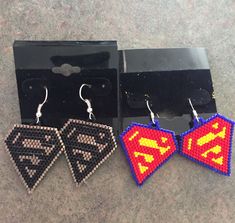 two pairs of earrings made out of legos are shown in front of a black box