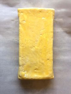 a piece of yellow cheese sitting on top of a metal counter next to a knife