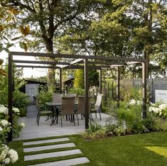 an outdoor dining area in the middle of a garden with white flowers and greenery