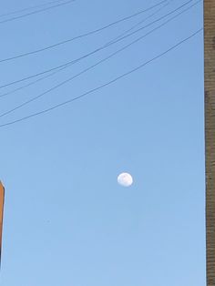 the moon is visible in the sky above power lines and telephone poles on a clear day