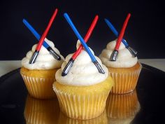 three cupcakes with white frosting and star wars straws on top are sitting on a black plate