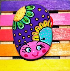 a colorful painted rock sitting on top of a wooden bench