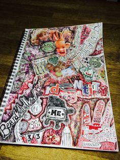 a spiral notebook covered in lots of stickers and writing on top of a wooden table