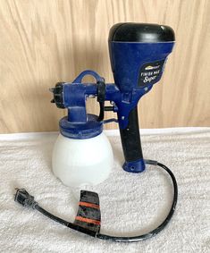 a blue and white paint sprayer sitting on top of a bed next to a cord