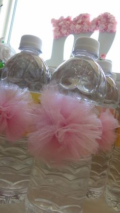 three plastic water bottles with pink tulle on them sitting in front of a window