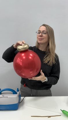 a woman holding a red balloon in front of her face