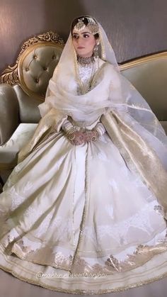 a woman in a white wedding dress sitting on a couch with a veil over her head