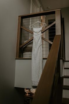 a wedding dress hanging on a rail next to stairs