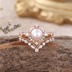 a pearl and diamond ring sitting on top of a piece of wood next to flowers