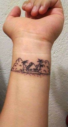 a small wrist tattoo with palm trees and houses on the beach in front of it