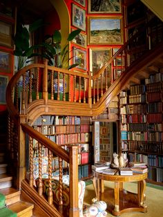 there is a spiral staircase in the room with bookshelves and paintings on the wall