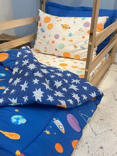 a child's bed with space themed sheets and pillows