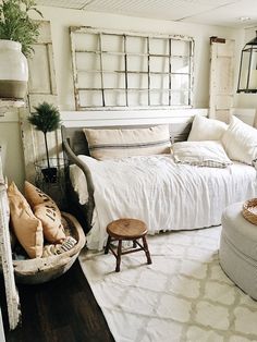 a white bed sitting in a bedroom next to a wooden table and window sill