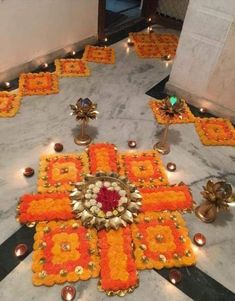 an arrangement of flowers and candles on a marble floor in front of a wall with lights