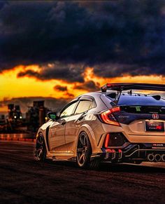 the rear end of a car parked in front of a sunset