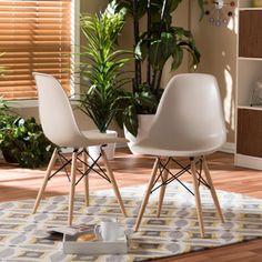 two white chairs sitting next to each other on top of a rug in a living room