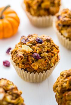 several muffins sitting on top of a white table next to small pumpkins