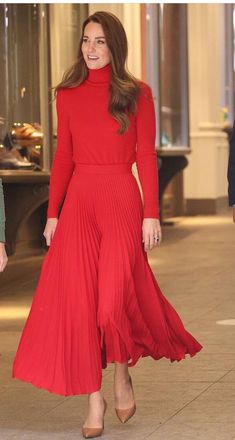 a woman in a red dress is walking down the street