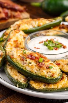 an assortment of food on a plate with dip in the middle and green peppers around it