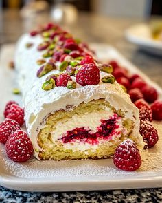 a cake with raspberries and pistachios is on a white plate