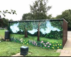 a painting on the side of a fence with trees, flowers and grass in front of it