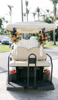 a white golf cart with flowers on the front and back seats is parked near some palm trees