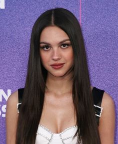 a woman with long brown hair wearing a white top and black dress at an event