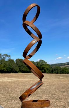 a metal sculpture in the shape of a spiral on top of a wooden table outside