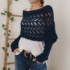 a woman standing in front of a ladder wearing a blue knitted sweater and jeans