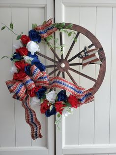 an old wagon wheel decorated with red, white and blue flowers is hung on the door