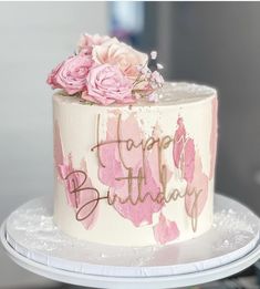 a birthday cake decorated with pink flowers and the words happy birthday written on its side