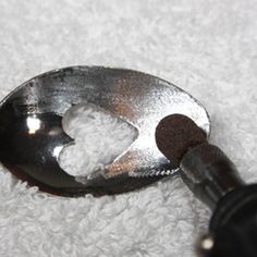 a close up of a metal spoon with a black handle on top of white carpet