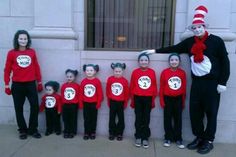 the cat in the hat is standing next to a group of children wearing red shirts