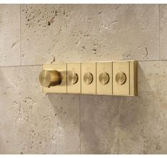 four brass colored knobs on the side of a wall mounted toilet paper dispenser