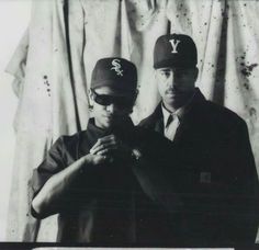 two men in baseball caps standing next to each other with their hands on their hips