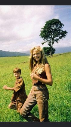 a woman standing next to a boy in a field