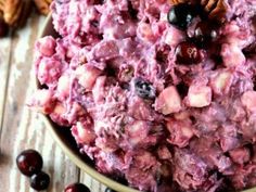 a bowl filled with fruit and nuts on top of a wooden table next to cranberries