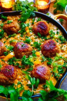 a pan filled with meatballs covered in cheese and garnished with parsley