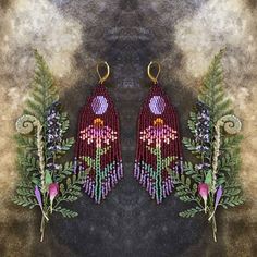 a pair of beaded earrings with purple flowers and green leaves on a dark background