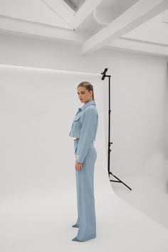 a woman standing in front of a white backdrop wearing a blue suit and matching heels