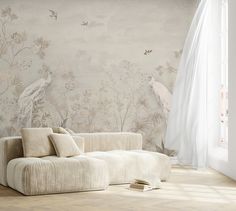 a white couch sitting in front of a window next to a wall with birds on it