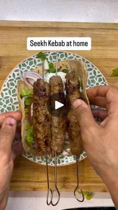 two hands holding kebabs on a plate with lettuce and onions in it