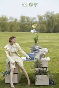 a woman sitting on top of boxes in the grass with flowers and plants growing out of them