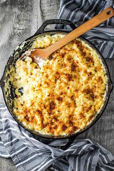 a skillet filled with macaroni and cheese on top of a striped cloth