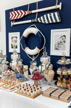 a table topped with lots of desserts and candies next to a blue wall