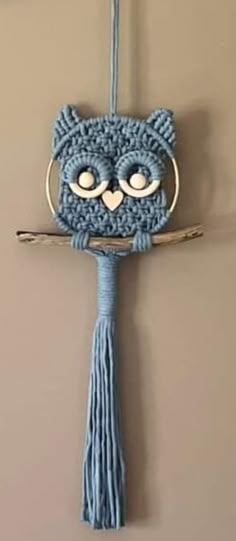 a crocheted cat hanging from a hook on a wall with a tassel