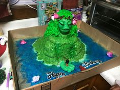 a green monster cake sitting in a box on top of a counter